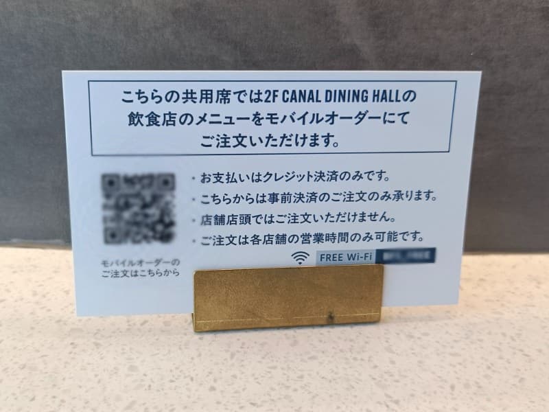 CNALA DINING HALLの共有席に置かれた案内